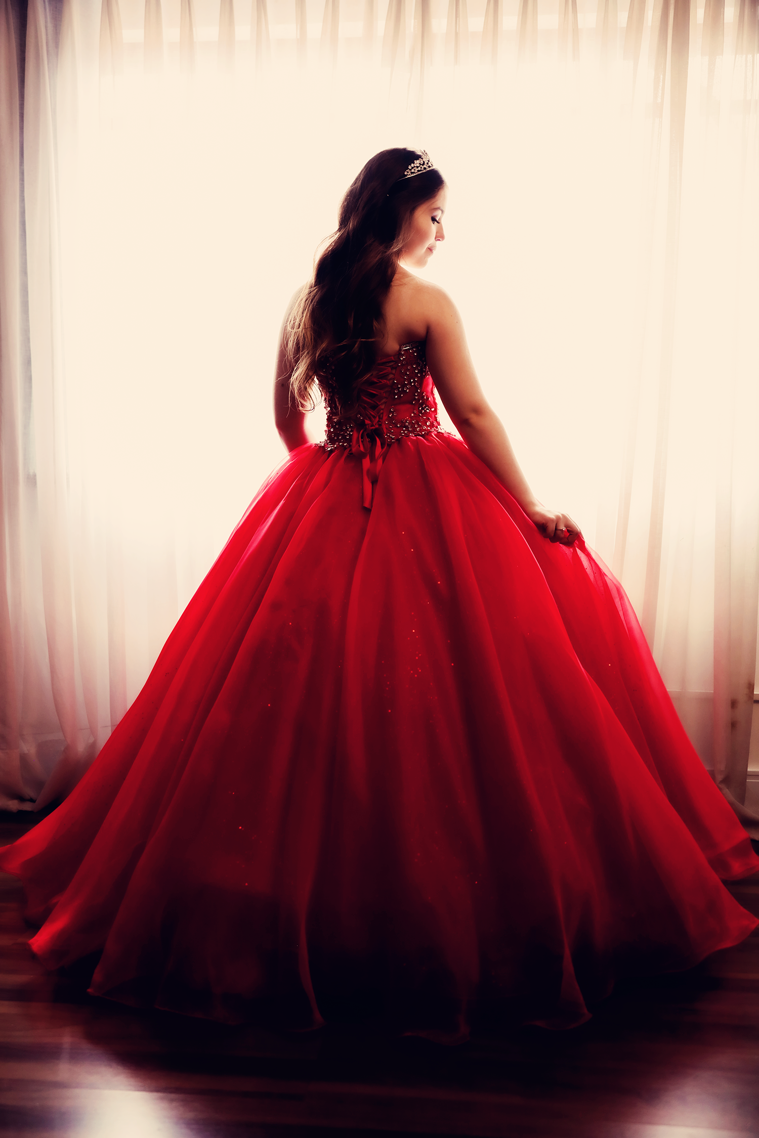 Debutante vestindo vestido de gala vermelho rodado com tiara em ensaio fotográfico de 15 anos no Estúdio Roni Sanches.