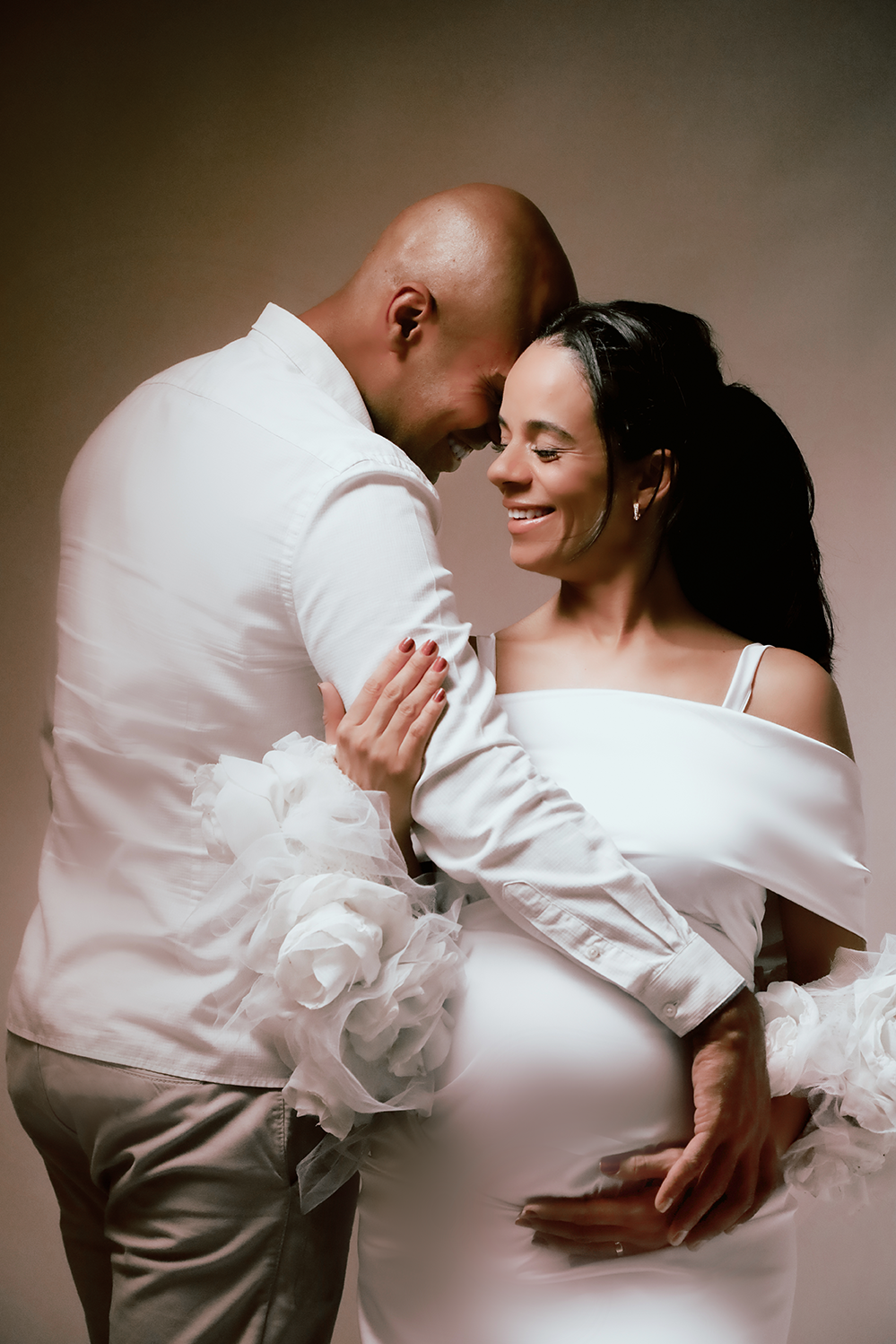 Fotos de grávida em casal durante ensaio de gestante em São Paulo: marido e esposa abraçados com as mãos na barriga.